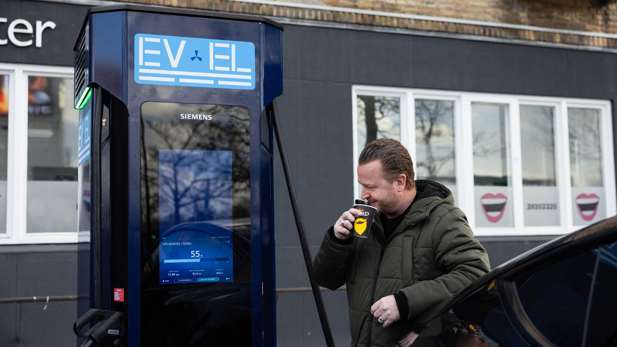 Man drinking coffee at an EV-EL fast charger while the car charges